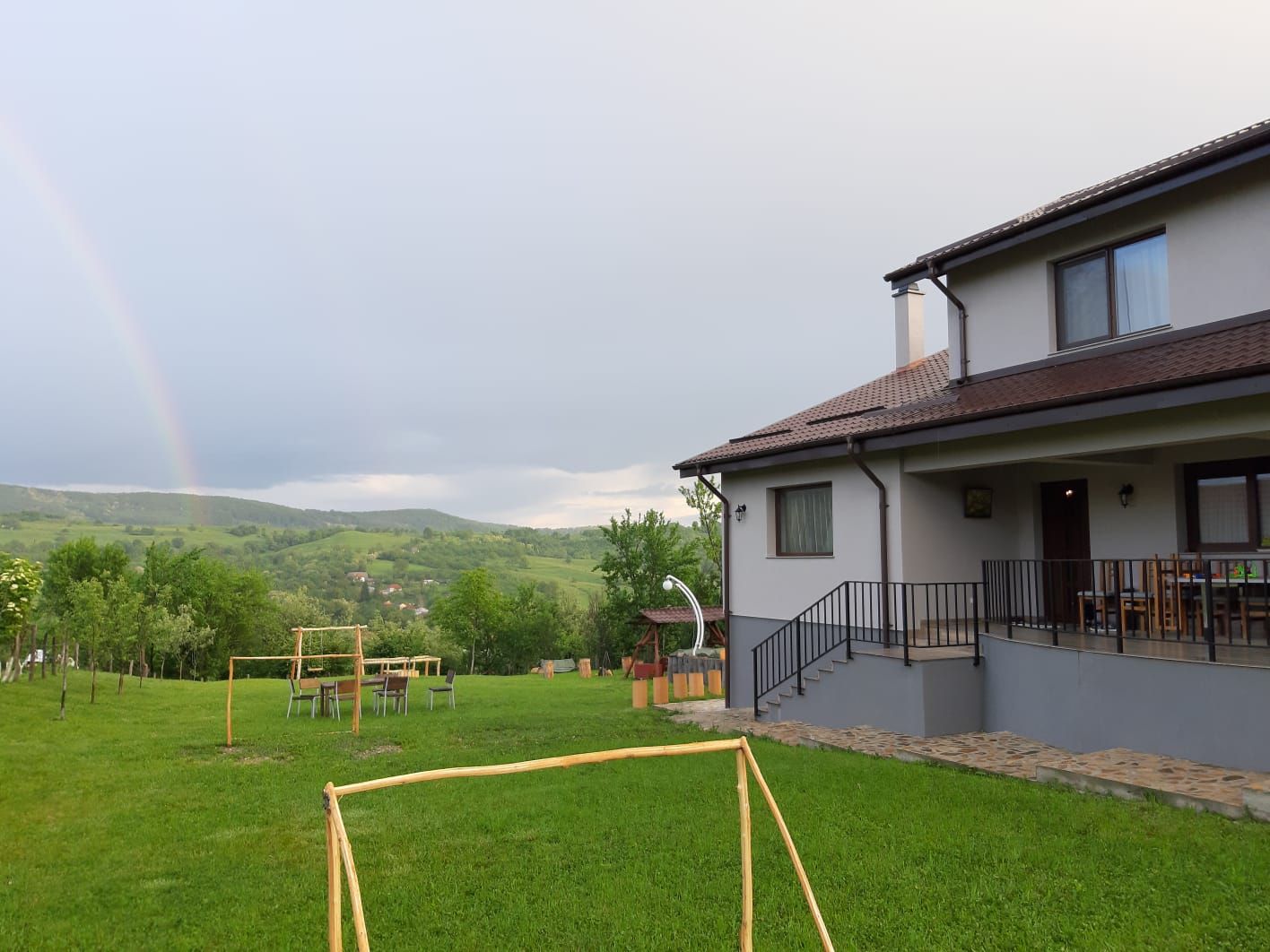 Curtea agropensiunii, cu un curcubeu peste vale